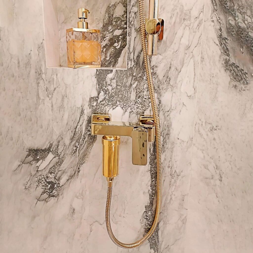 Guldbrusefilter monteret på bruser – elegant løsning, der reducerer kalkaflejringer og beskytter både hud, hår og armaturer mod hårdt vand.