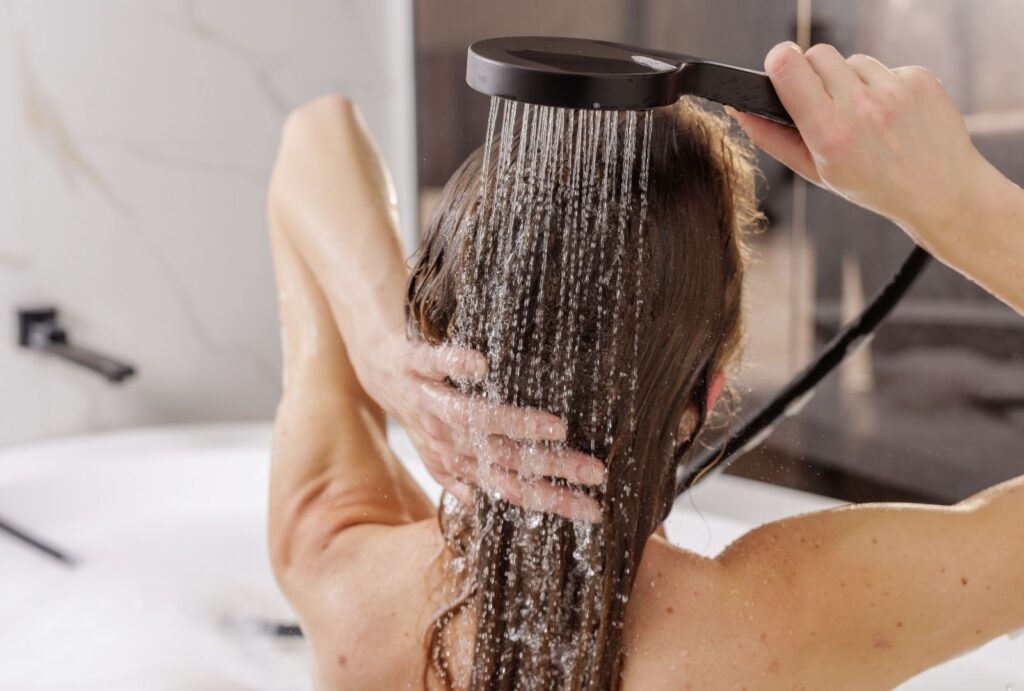 Kvinde nyder brusebad med blødt vand fra blødgøringsanlæg – skånsomt mod hud og hår og uden kalkrester på fliser og armaturer.